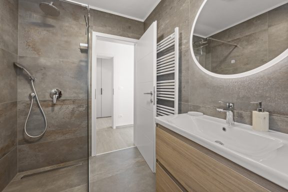 Moderne Badezimmeransicht mit Dusche, Waschbecken und neutralen Farbtönen.