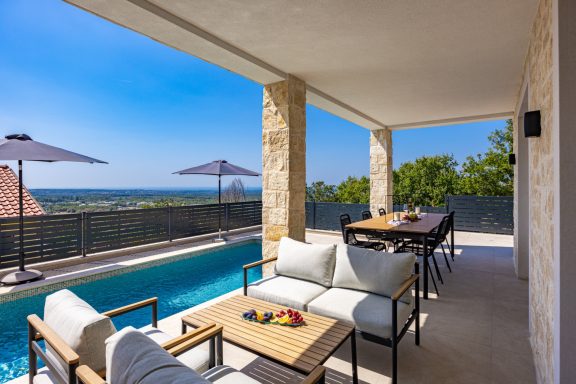 Luxuriöse Terrasse mit Sitzbereich, Essplatz und Blick auf den Pool und die Landschaft.